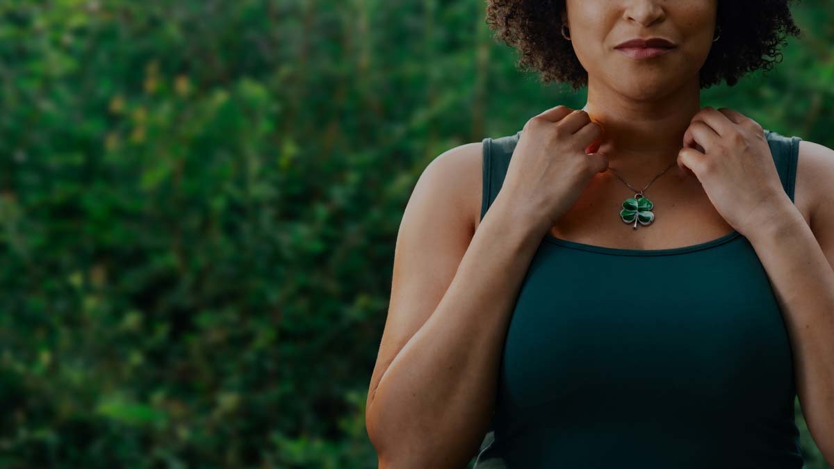 Woman contemplating the luck her four-leaf clover necklace could bring her.