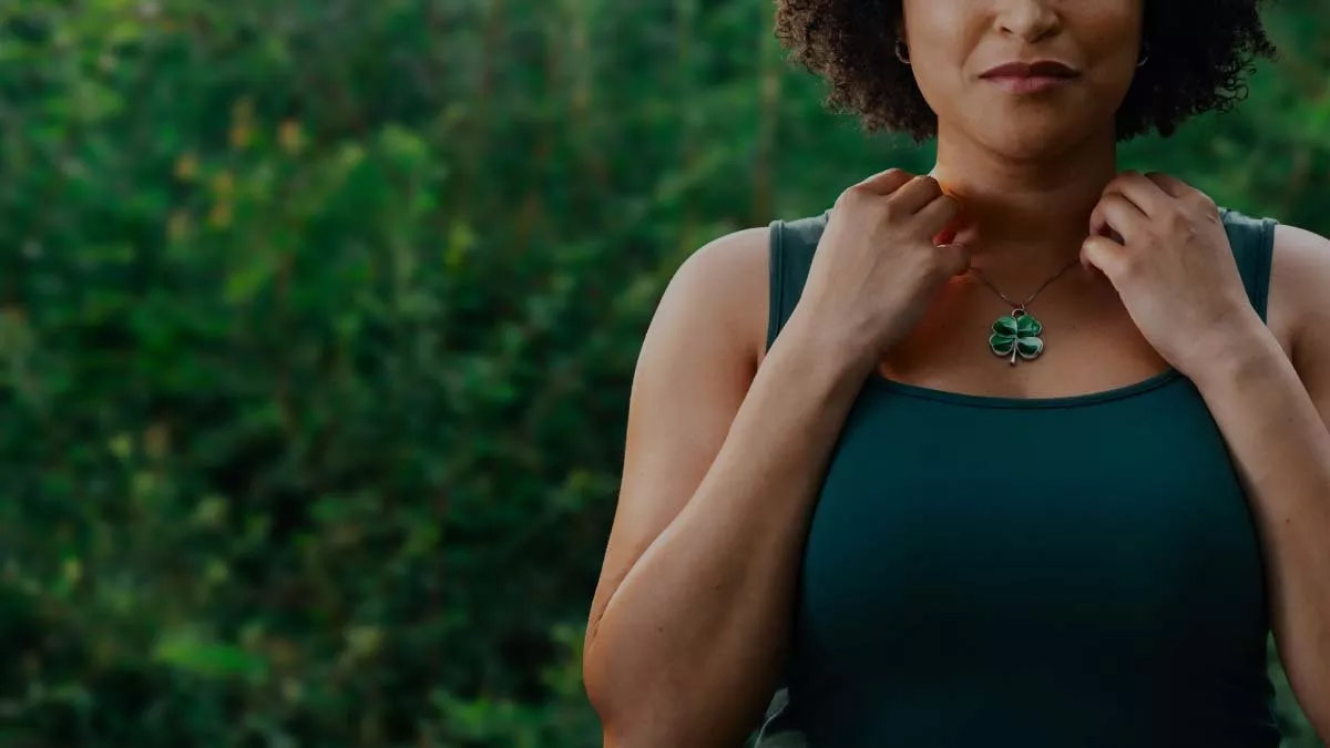 Woman contemplating the luck her four-leaf clover necklace could bring her.