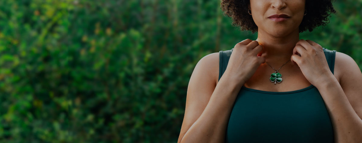 Woman contemplating the luck her four-leaf clover necklace could bring her.